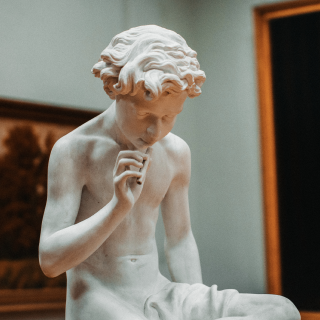 A statue of a boy in a museum trying to recall something