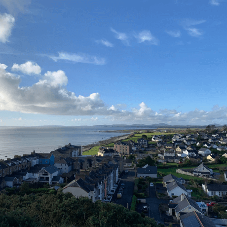 A picture of Cricieth, Wales with many small houses, the sea, and the bright blue sky