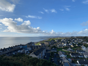 A picture of the countryside with many small houses, the sea, and the bright blue sky