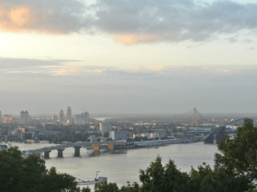 A picture of a big city with many buildings, a big river, a big bridge, and the cloudy sky